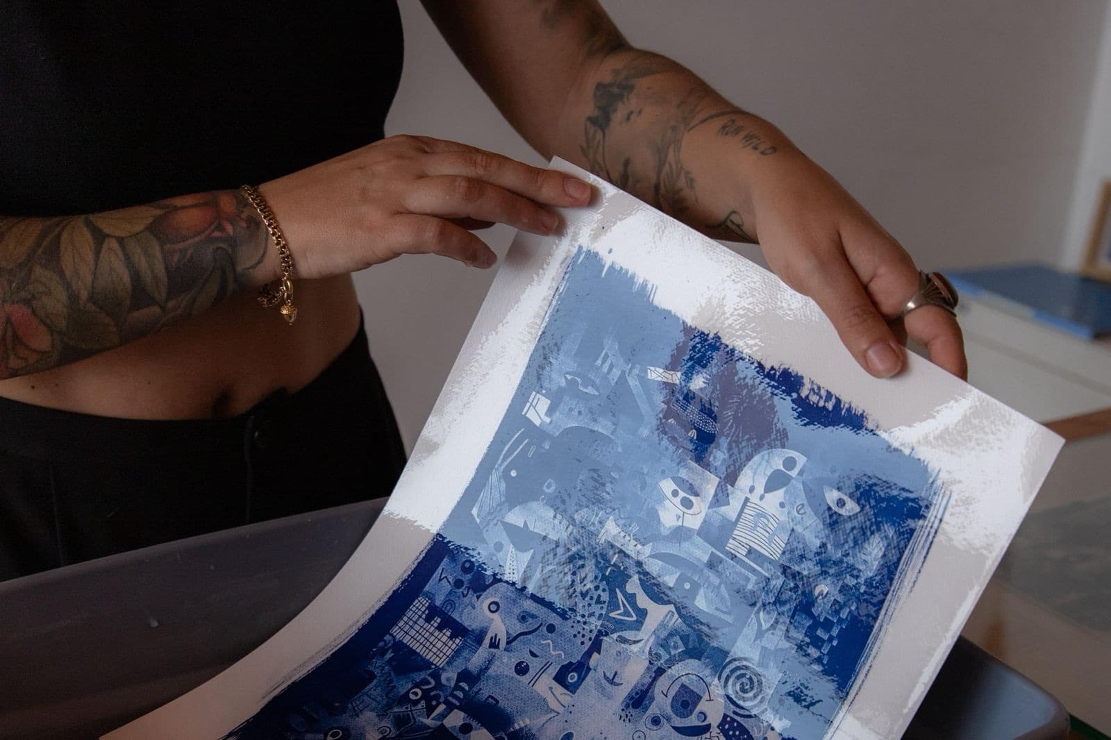Mãos a segurar uma cianotipia acabada de revelar, em tons de azul